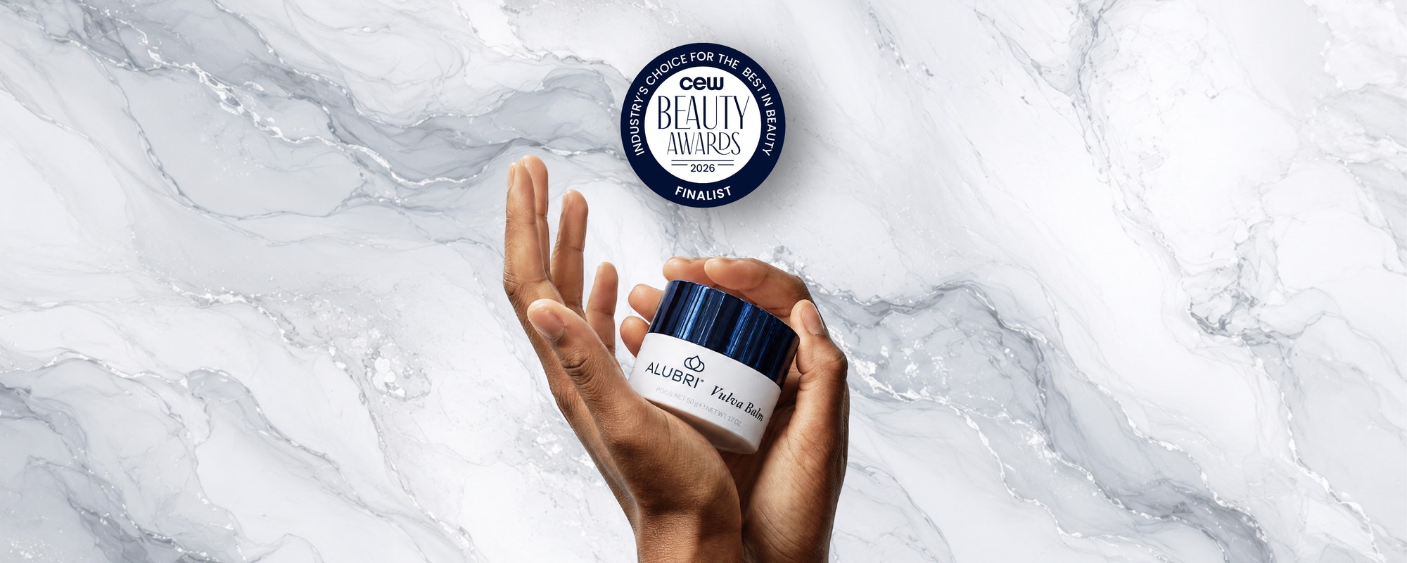 A person's hands holding a white cosmetic jar with a dark blue lid, set against a white and gray marble background. A circular 'CEWI Beauty Awards Finalist' badge is floating above the hands.